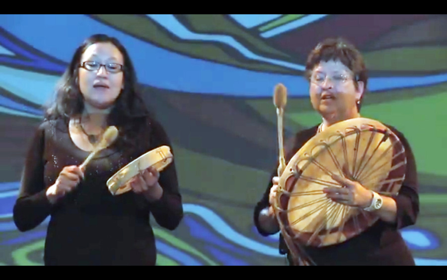 two women with hand-drums, singing